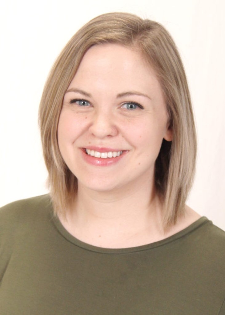A smiling woman with shoulder-length straight hair, wearing a green shirt, poses against a light background.