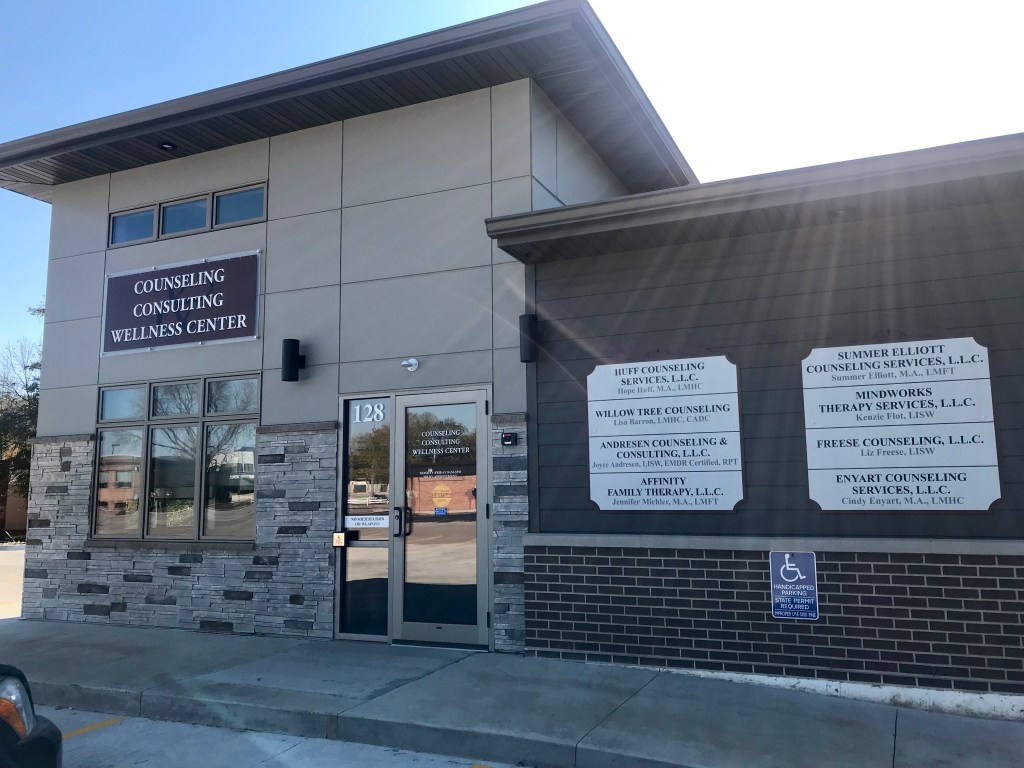 Exterior view of a counseling and wellness center building with multiple service providers listed on the facade.